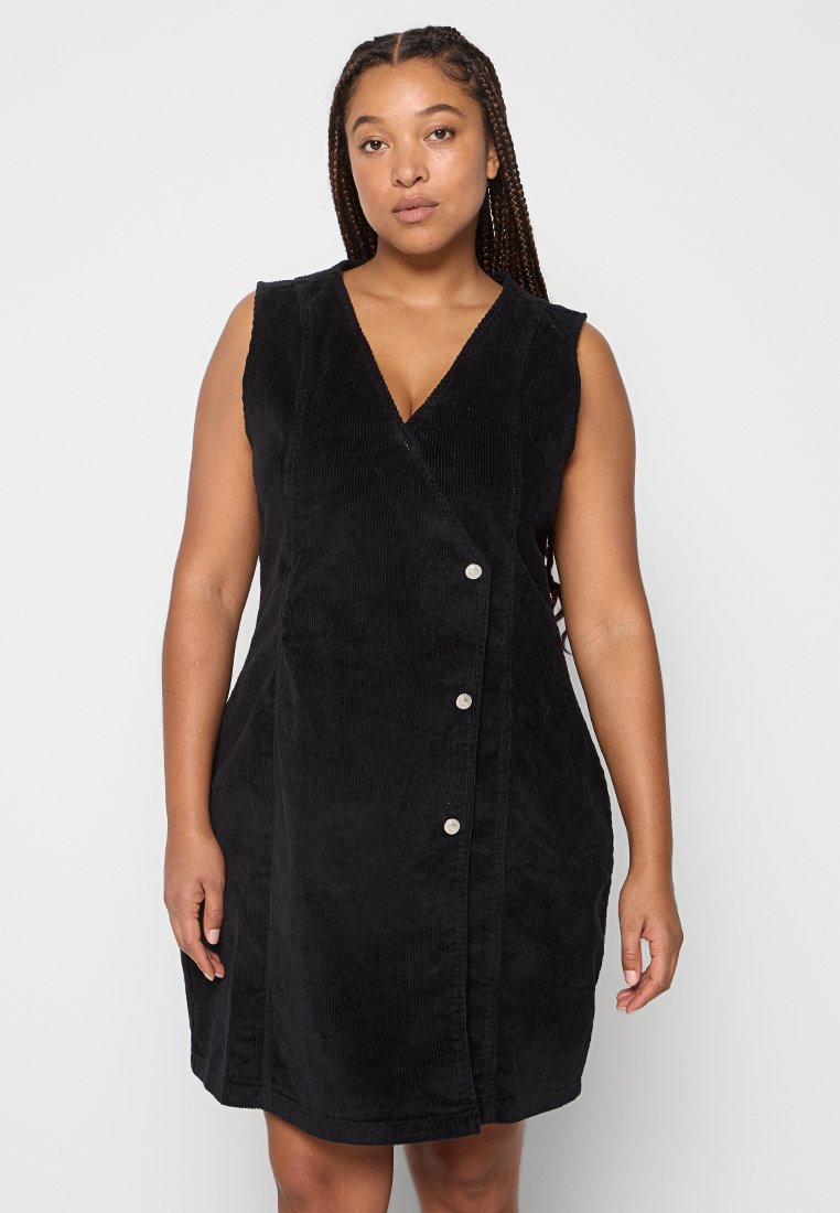 Schwarzes Ripp-Kleid ohne Ärmel mit V-Ausschnitt, das ein Wickeldesign aufweist und drei silberne Knöpfe vorne hat. Glatte Textur und figurbetonte Form.