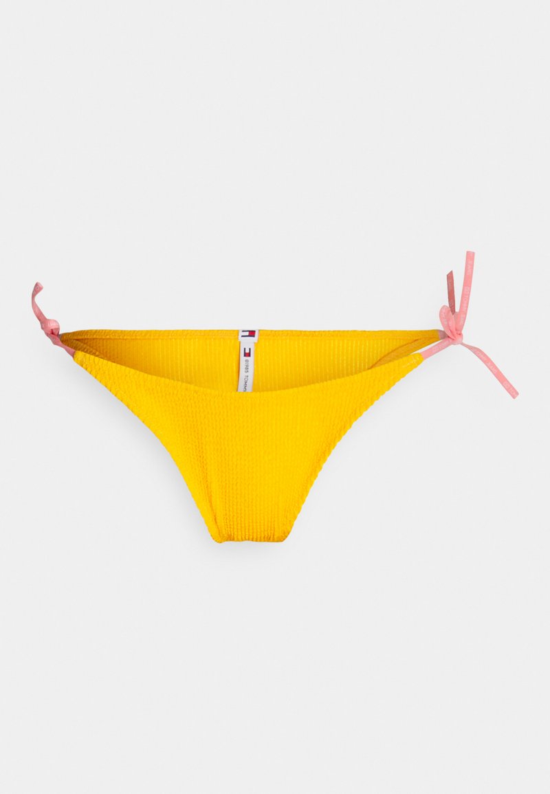 Gelber Bikini-Höschen mit gerippter Textur, ausgestattet mit seitlichen Bindebändern in Hellrosa und einem kleinen Markenetikett auf der Innenseite.