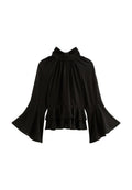 Schwarze Bluse mit langen Ärmeln und kleinen weißen Punkten, hoch gebündeltem Ausschnitt, ausladenden Ärmeln und Rüschendetail am Saum.