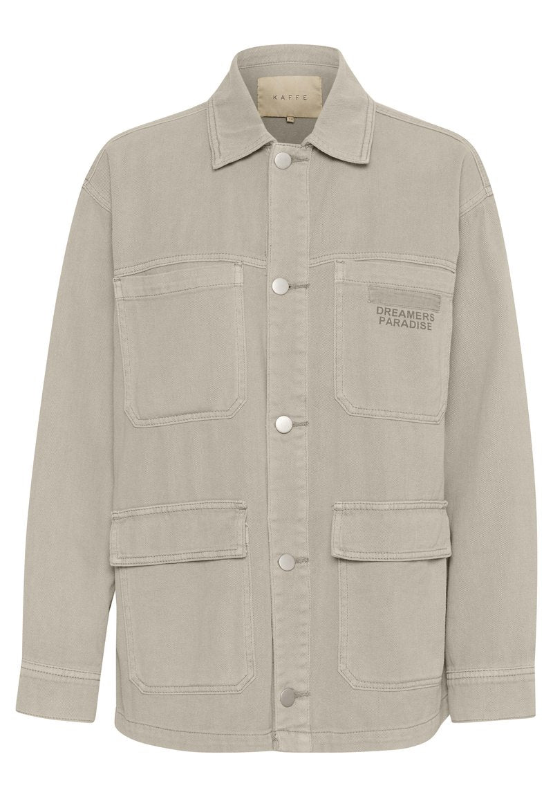 Beige Jeansjacke mit klassischem Kragen, vorderer Druckknopfverschluss und vier Taschen. "DREAMERS PARADISE" auf der linken Brust gestickt.