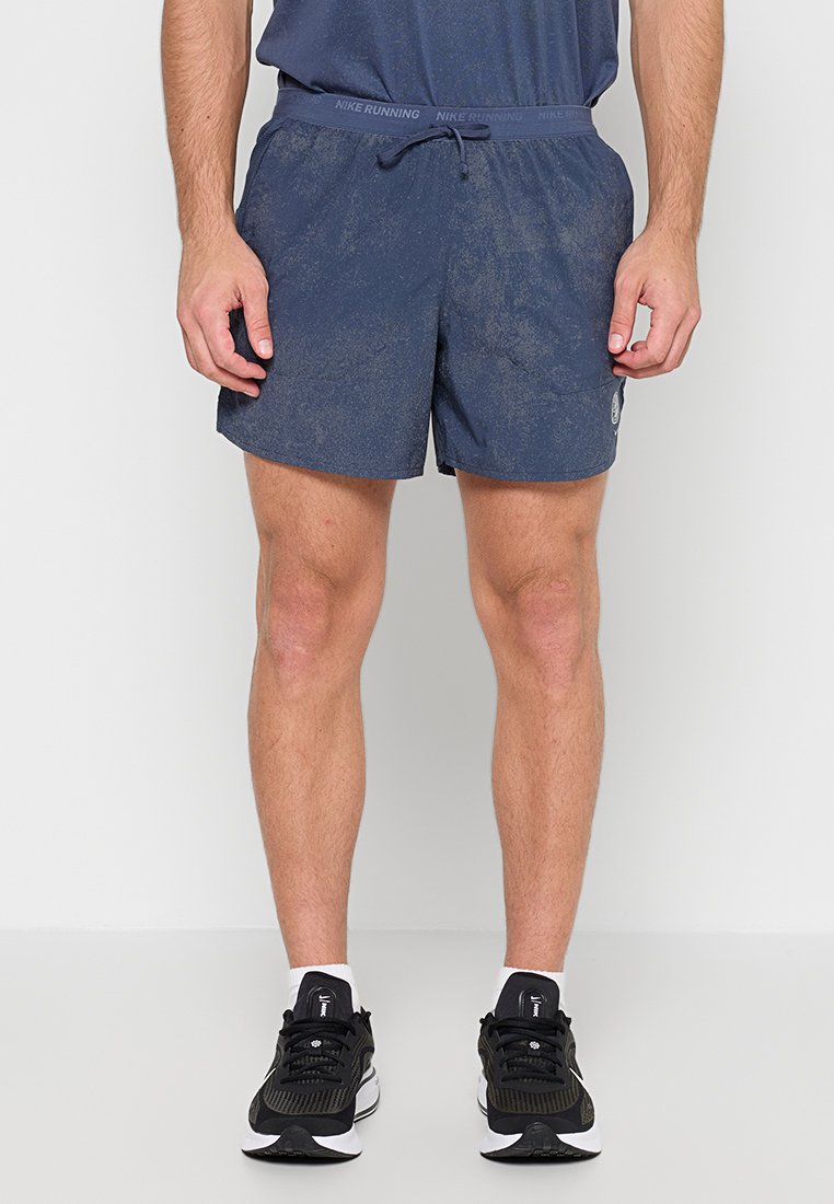 Mann trägt marineblaue Nike Laufshorts mit elastischem Bund und schwarze Nike Laufschuhe mit weißen Sohlen.