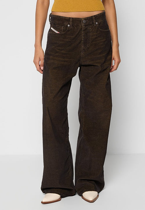 Dunkelbraune Cordhose im weiten Schnitt mit strukturiertem Finish, ausgestattet mit vorderen Taschen und einem Knopfverschluss, kombiniert mit beigen spitzen Schuhen.