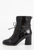Schwarze Leder-Ankelboots mit glänzender Oberfläche, vorn zum Schnüren, mit goldenen Ösen und zylindrischem hohen Absatz.