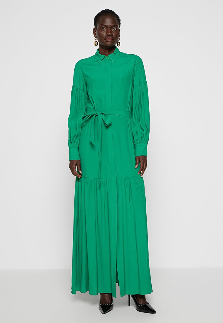 Grünes, langärmeliges Maxikleid mit kragenlosem Halsausschnitt, gerafftem Taillenzug und gestuftem Rock. Glattes Material mit fließender Silhouette.