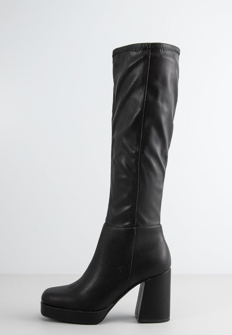 Schwarze kniehohe Stiefel aus glattem synthetischem Material, mit einem klobigen hohen Blockabsatz und einem eng anliegenden Schaft mit minimalem Nähdetail.