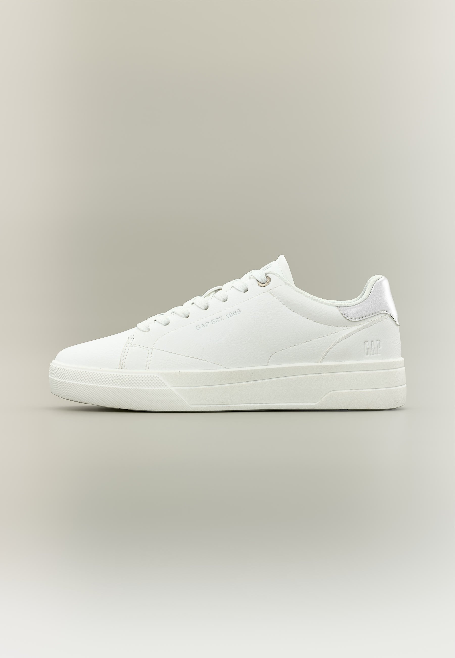 Weißer Sneaker mit niedrigem Schaft, Schnürsenkeln, dezentem Markenlogo an der Seite und Ferse sowie Gummisohle auf neutralem beigem Hintergrund.