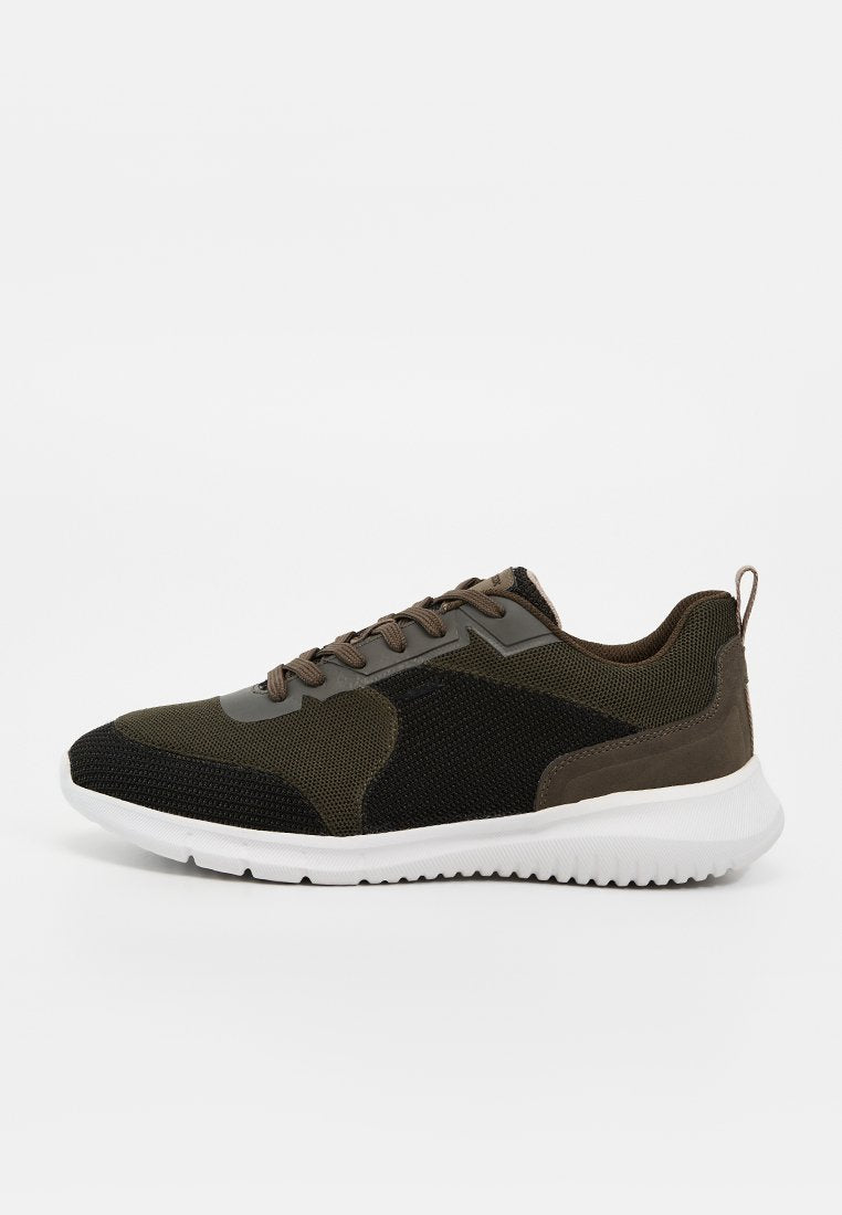 Flacher Sportschuh in Schwarz und Olivgrünem Mesh mit braunen Schnürsenkeln und weißer, strukturierter Gummisohle, seitliche Ansicht.