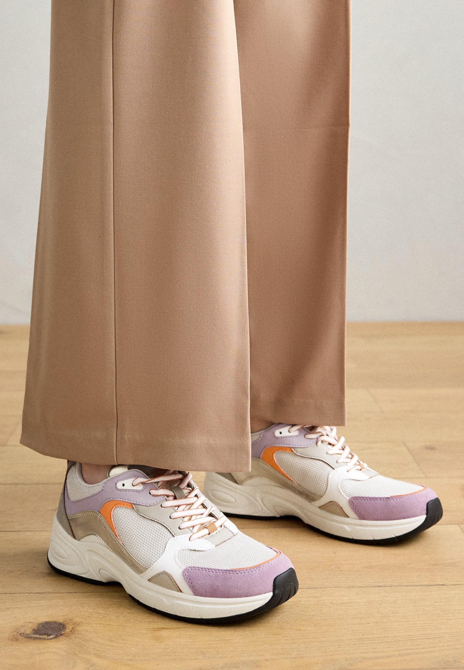 Sneaker in Weiß, Lila und Orange mit Mesh- und Wildledermaterialien. Verfügt über einen gepolsterten Kragen, eine kontrastierende Sohle und auffällige Schnürsenkel.