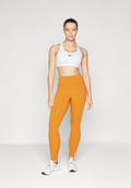 Weißer Sport-BH mit schwarzem Logo, kombiniert mit orangefarbenen, hoch taillierten Leggings. Das Model trägt schwarze und weiße Sneakers und steht vor einem hellen Hintergrund.