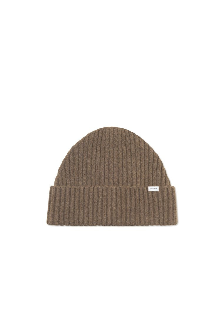 Braune ribbelige Strickmütze mit umgeschlagenem Bündchen. Aus weichem Stoff gefertigt, mit einem kleinen Etikett am Bündchen. Kompakte und runde Form.