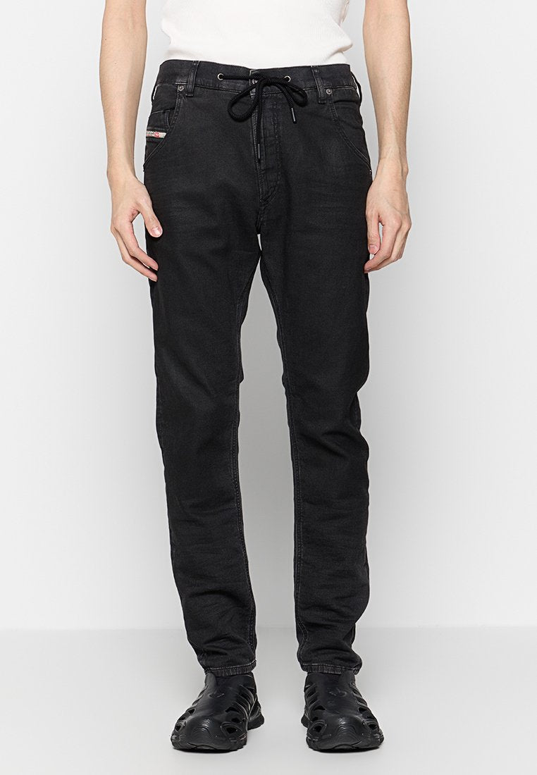 Schwarze Denim-Hosen im Slim-Fit mit einem Gummizugbund und Seitentaschen. Glatte Textur mit minimaler Gestaltung.