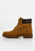 Brauner Veloursleder-Stiefelette mit gelben Schnürsenkeln, braunem Lederkragen, strukturierten Details und einem Logo an der Seite. Flache Gummisohle, robustes Design.