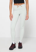 Hellgrüne Leggings mit hohem Bund, Kordelzugdetail und Seitentasche. Kombiniert mit dunkelroten Sportschuhen und weißen Socken.