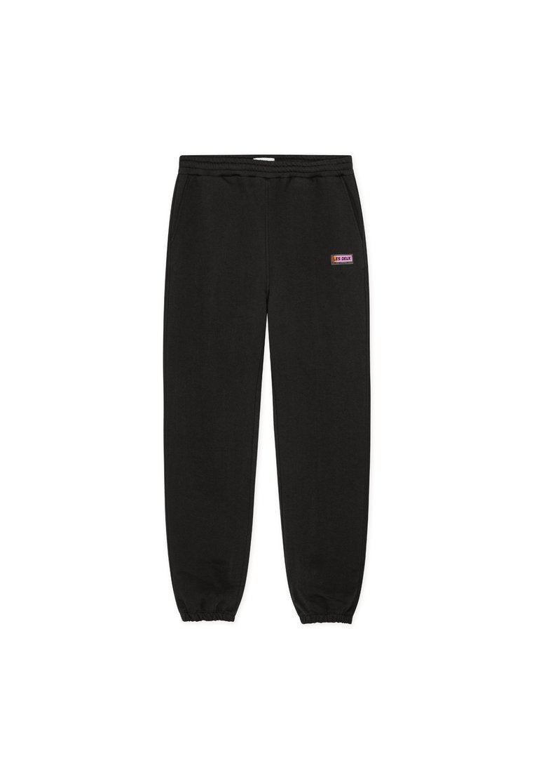 Schwarze Jogginghose mit elastischem Bund und zulaufenden Bündchen, ausgestattet mit einem kleinen rechteckigen Logo-Patch in Lila und Weiß.