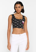 Schwarzes Crop-Top mit quadratischem Ausschnitt, gemustert mit Kreisen und einem rosa Herzakzent. Hat kurze Träger und ein Knopfdetail in der Mitte.