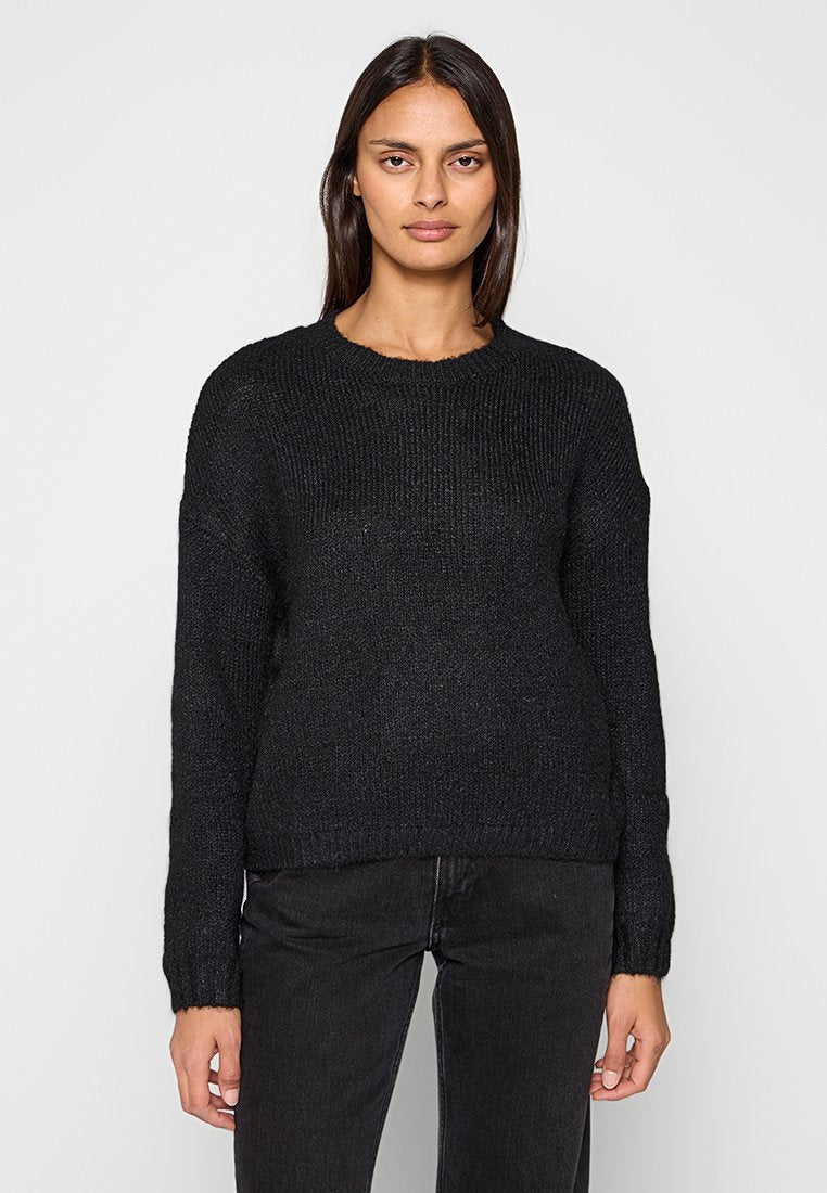Schwarzer gestrickter Pullover mit rundem Ausschnitt und langen Ärmeln, mit einem strukturierten Muster und lässiger Passform, getragen zu dunklen Jeans.