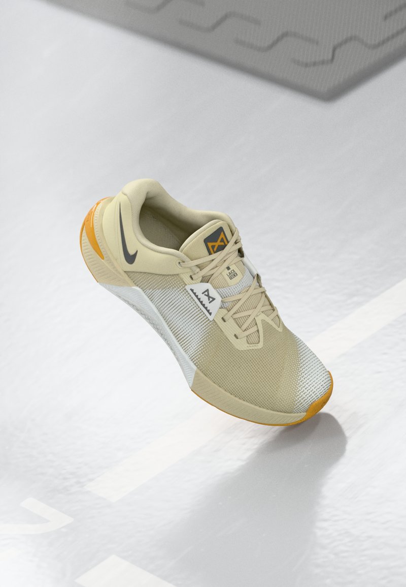 Beige Sportshoe mit mesh-Obermaterial, grauen Akzenten und orangefarbener Gummisohle. Verfügt über Schnürsenkel, Logo auf der Zunge und strukturiertes Design an der Seite.