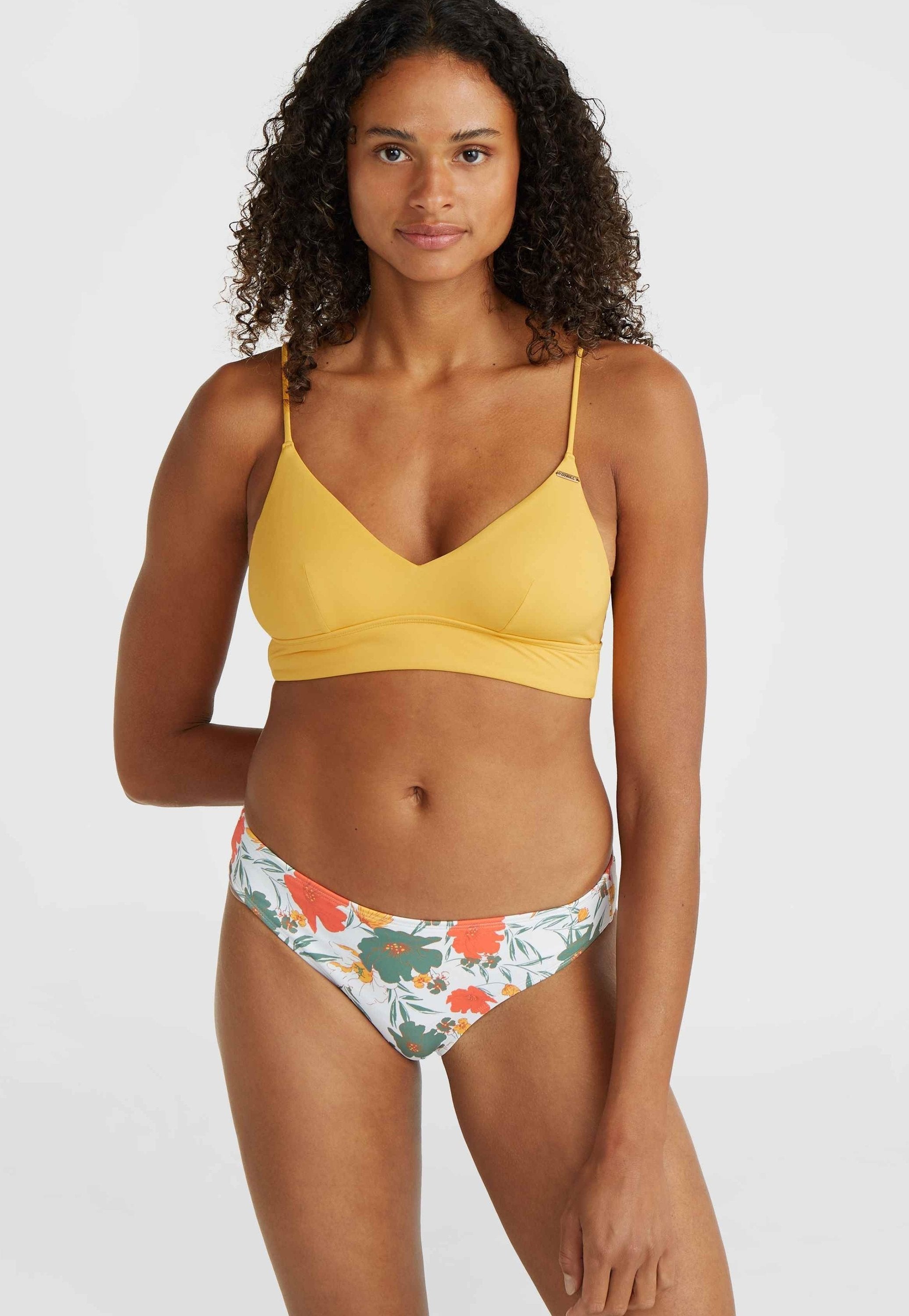 Gelber Bikini-Oberteil mit V-Ausschnitt und dünnen Trägern, kombiniert mit floral gemusterten, niedrig geschnittenen Bikiniunterteilen in Grün, Orange und Weiß.