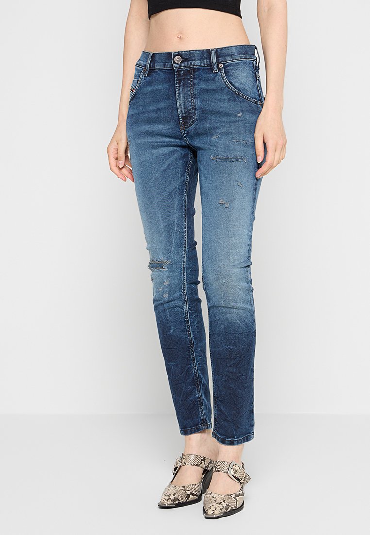 Ausgewaschene blaue Denim-Jeans mit abgenutzten Stellen und schmalem Schnitt, mit einem Knopfverschluss und fünf Taschen. Stylisch kombiniert mit gemusterten Pumps.