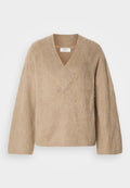 Beige, flauschiger Strickpullover mit weitem V-Ausschnitt und langen Ärmeln, auf einem weißen Hintergrund präsentiert.