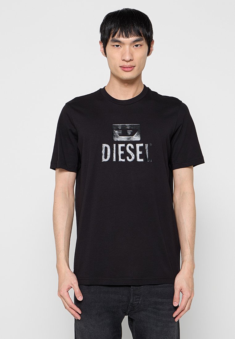 Schwarzes Baumwoll-T-Shirt mit einem auffälligen weißen Diesel-Logo auf der Vorderseite, kurzen Ärmeln, Rundhalsausschnitt und lockerem Schnitt.