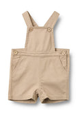 Beige Baumwoll-Overalls mit verstellbaren Trägern, vorderen Knopfverschlüssen, zwei Seitentaschen und einem Druckknopfverschluss am unteren Ende für einfaches An- und Ausziehen.