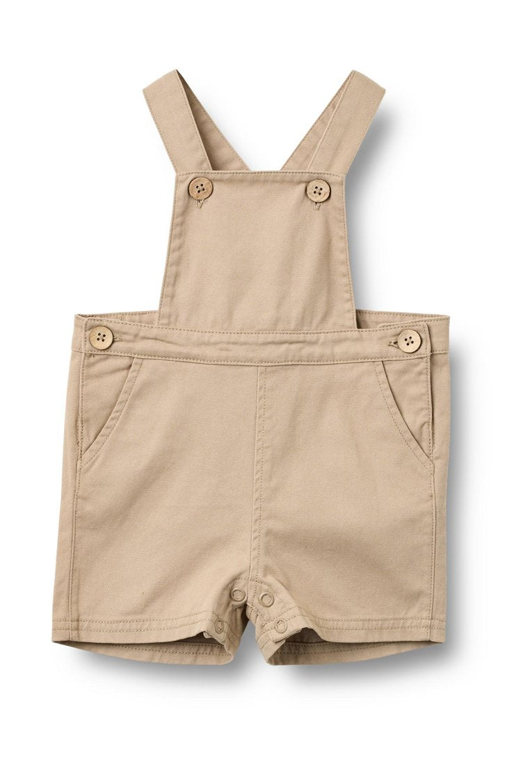 Beige Baumwoll-Overalls mit verstellbaren Trägern, vorderen Knopfverschlüssen, zwei Seitentaschen und einem Druckknopfverschluss am unteren Ende für einfaches An- und Ausziehen.