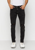 Schwarze Jeans aus Denim mit schmaler Passform, die abgenutzte Knie-Risse, fünf Taschen und einen Knopfverschluss aufweist. Kombiniert mit weißen Sneakers.