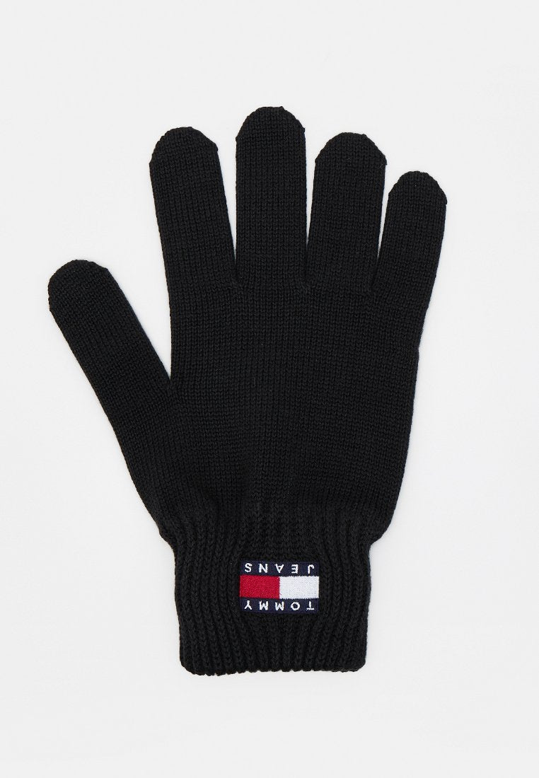 Schwarzer Strickhandschuh mit fünf Fingern und einem aufgenähten Tommy Jeans Logo in Rot, Weiß und Blau auf der Handgelenksmanschette.
