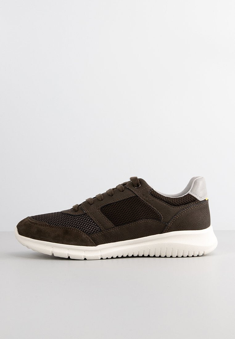 Dunkelbraune Sneaker mit einem Obermaterial aus Mesh und Wildleder, weißer strukturierten Gummisohle und einem weißen gepolsterten Kragen vor einem schlichten hellen Hintergrund.