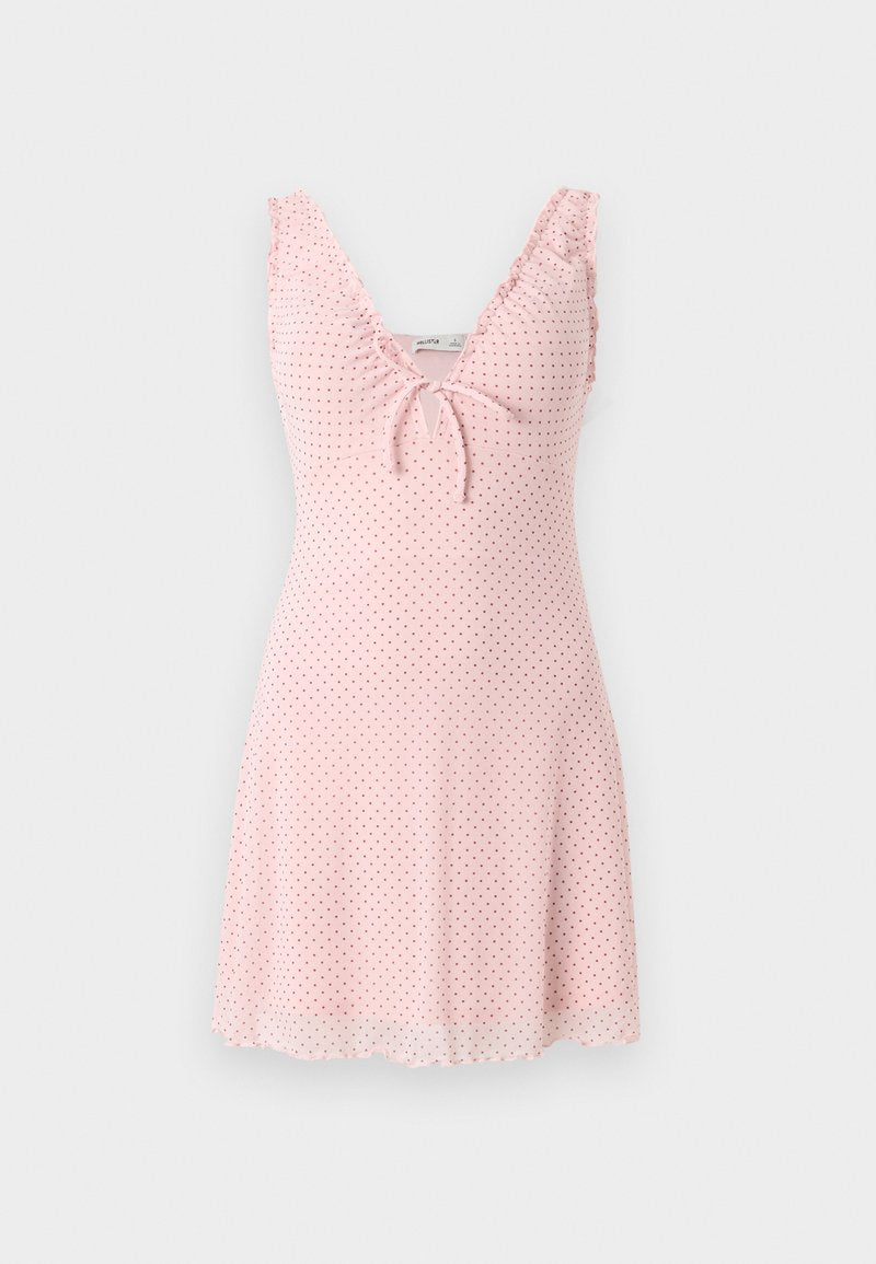 Hellrosa ärmelloses Kleid mit kleinen schwarzen Polka-Dots, V-Ausschnitt, vorderer Bindierung und Rüschen an den Schulterriemen.