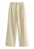 Beige weite Hosen aus einem weichen Stoff, mit Vorderfalten, Gürtelschlaufen und Seitentaschen. Glatte Textur mit minimalistischem Design.