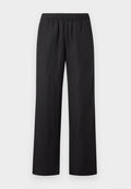 Schwarze locker sitzende Hose mit elastischem Bund und seitlichen Taschen, vor hellem, einfarbigem Hintergrund präsentiert.