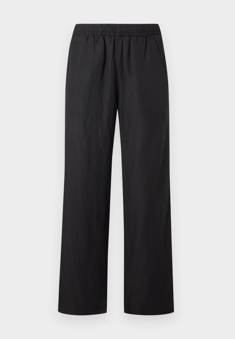Schwarze locker sitzende Hose mit elastischem Bund und seitlichen Taschen, vor hellem, einfarbigem Hintergrund präsentiert.