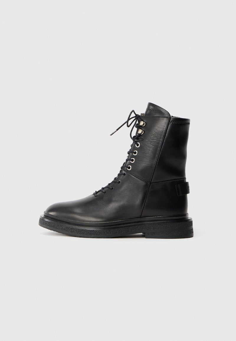 Schwarze Leder-Ankle-Boots mit Schnürung, silbernen Ösen, strukturiertem schwarzen Gummisohle und gepolsterter Lasche für zusätzlichen Komfort.