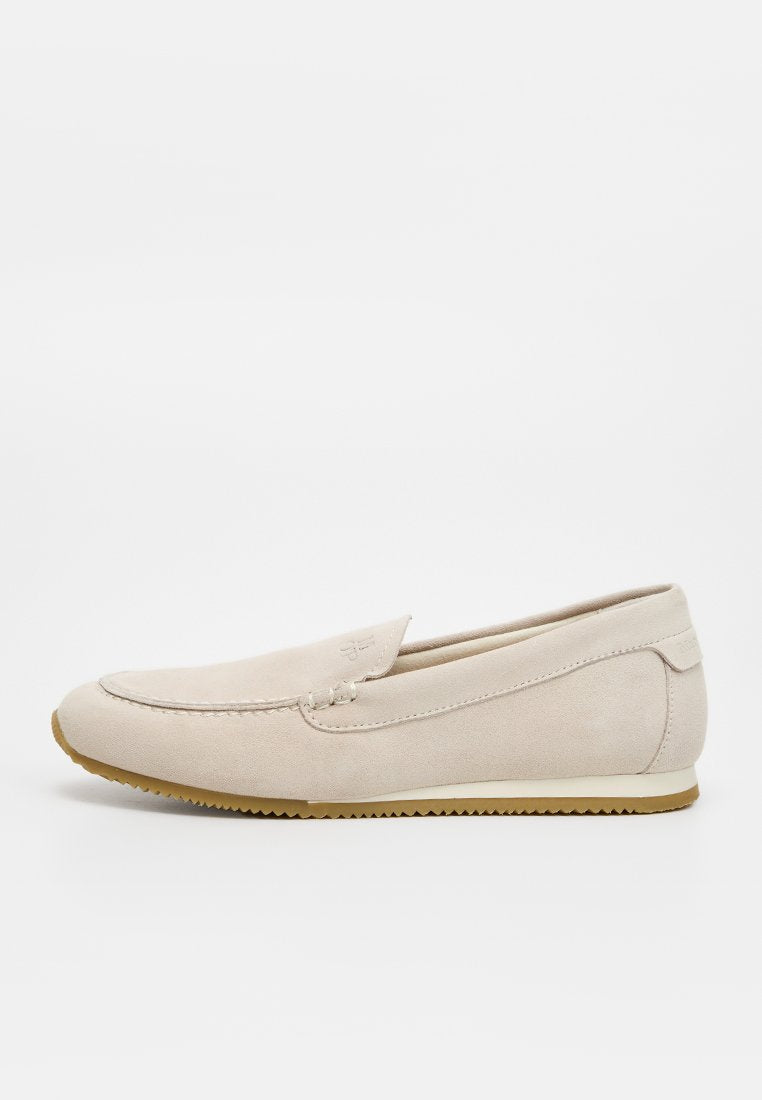 Beiger Wildleder-Slipper mit Ziernähten, rundem Zehenbereich, niedrigem Absatz und Gummisohle, seitlich auf weißem Hintergrund gezeigt.