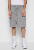 Graue Sportshorts mit strukturiertem Muster, elastischem Bund, Seitentaschen und Logo-Detail; kombiniert mit weißen Socken und Turnschuhen.