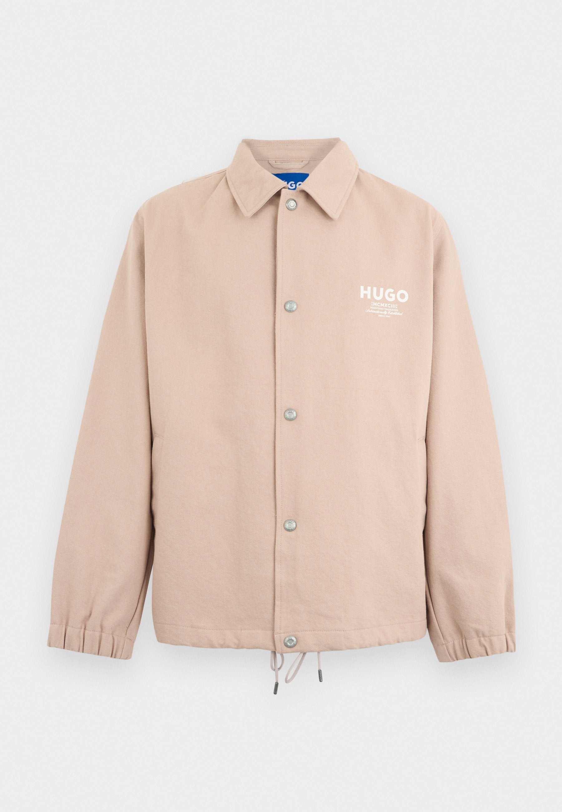 Beige Jacke mit Knöpfen, Kragen, elastischen Bündchen, Kordelzug am Saum und weißem "HUGO"-Logo auf der linken Brust.