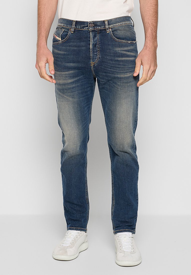 Herren dunkelblaue Denim-Jeans mit leichter Ausbleichung, Knopfverschluss und vier Taschen. Kombiniert mit weißen Sneakern.