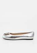 Silberfarbener metallischer Ballerina-Schuh mit schwarzer Sohle und goldenem dekorativem Emblem an der abgerundeten Spitze, dargestellt vor weißem Hintergrund.