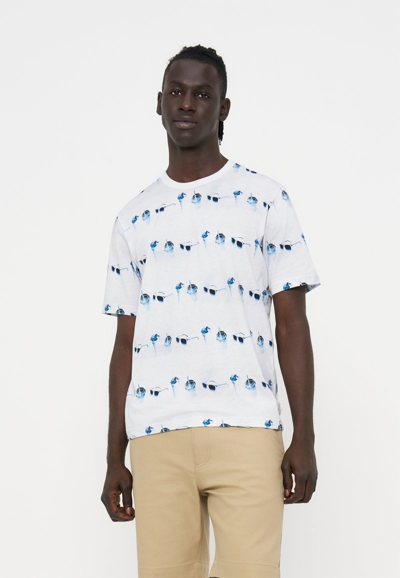 Mann trägt ein weißes kurzärmliges T-Shirt mit einem blauen Sonnenbrillen- und Getränke-Muster und beigen Shorts auf weißem Hintergrund.