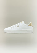 Weißer Sneaker mit niedrigem Schaft, goldfarbenem Absatzakzent, weißen Schnürsenkeln und "GAP"-Logo an der Seite, vor einem einfarbigen neutralen Hintergrund.