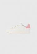 Weißer Sneaker mit niedrigem Schaft, goldenen Ösen, rosa Fersenpatch und dezenten perforierten Seitendetails auf hellgrauem Hintergrund.
