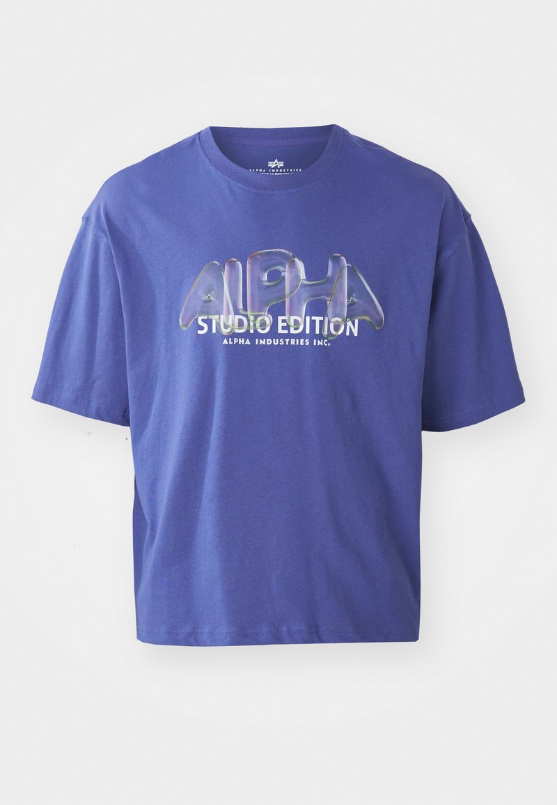 Lila Baumwoll-T-Shirt mit lockerer Passform, Rundhalsausschnitt und einem grafischen Druck, der in fetter Schrift "ALPHA STUDIO EDITION" abbildet.