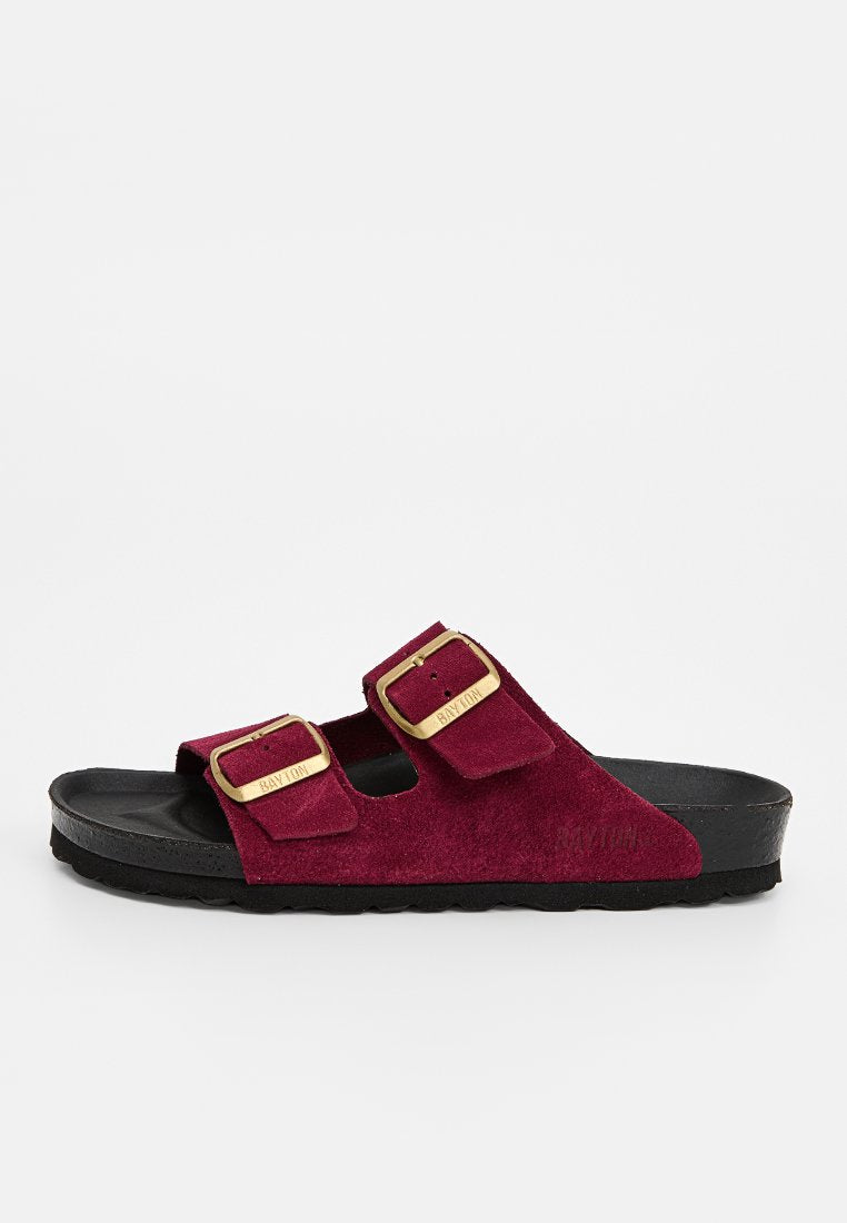 Ein einzelner halbhoher Wildleder-Slipper in Burgunderrot mit zwei verstellbaren Schnallen in Goldoptik und schwarzer konturierter Sohle.