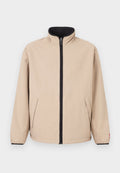 Beige Jacke mit hohem Kragen, Reißverschluss vorne und schwarzen Akzenten. Verfügt über zwei Seitentaschen und elastische Bündchen. Glatte Textur.