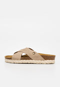 Beige Slip-On-Sandale mit gekreuzten Riemen, Korkfußbett, geflochtenem weißen Sohlenrand und kleinem rundem Metallknopf am Seitenriemen.