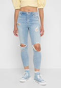Helle blaue Skinny-Jeans mit verwaschenen Details, einschließlich großer Knie-Risse und fransigen Kanten, aus Denim-Stoff.