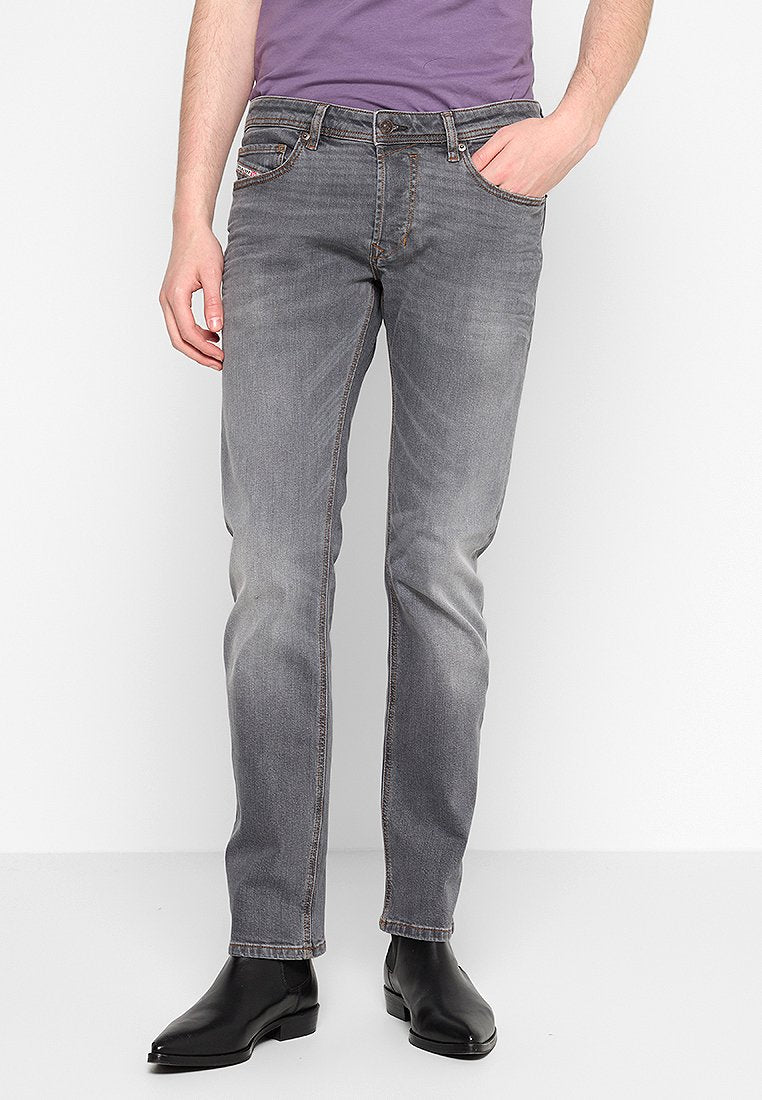 Graue Denim-Jeans mit schmaler Passform, ausgestattet mit einem verblassten Finish, fünf Taschen und kontrastierenden Nähten. Kombiniert mit schwarzen Ankle Boots.