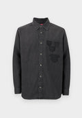 Schwarzes Denim-Hemd mit durchgehender Knopfleiste, langen Ärmeln, einem Kragen und drei bestickten Abzeichen auf der linken Brust. Strukturierter Stoff.